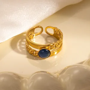 Dettaglio di anello doppio vintage dorato con pietra blu e trama a catena