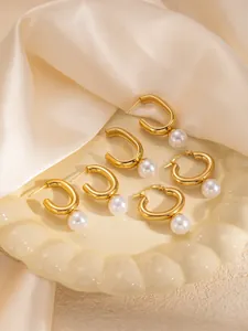 Dettaglio di orecchini con perle dorate su piatto di ceramica e seta color champagne