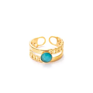 Dettaglio anello regolabile in oro con design a doppia catena e gemma verde