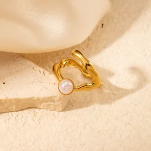 Dettaglio anello dorato irregolare con perla bianca e design vintage a onde