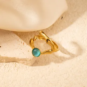 Macro di anello dorato irregolare con pietra occhio di gatto blu su tessuto di seta fine