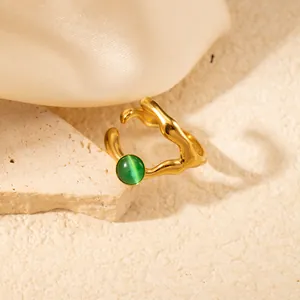 Dettaglio macro dell'anello dorato ondulato con pietra occhio di gatto verde