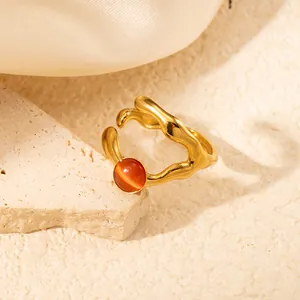 Dettaglio di un anello in titanio dorato ondulato con pietra occhio di gatto arancione