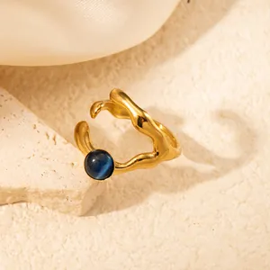 Dettaglio dell'anello dorato ondulato con pietra occhio di gatto blu in stile retrò