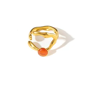 Dettaglio macro di un anello vintage dorato con trama irregolare e pietra centrale arancione
