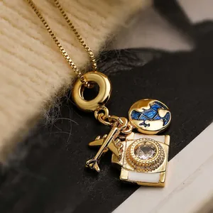 Exquisite gold necklace with globe, airplane, and camera charms on knitted background