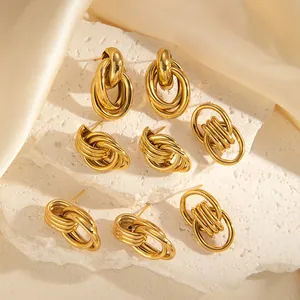 Close-up of three 18k gold plated chunky hoop earrings on a white stone background