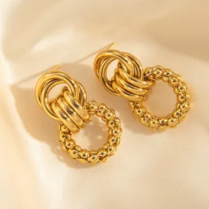 Close-up of vintage 18k gold plated earrings featuring intertwined rings and beaded texture