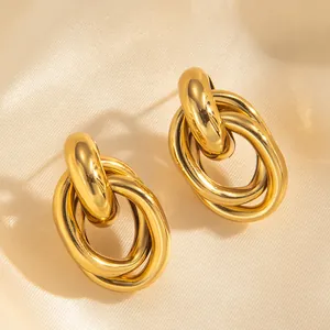 Macro shot of 18k gold plated triple-layered interlocking ring earrings on satin