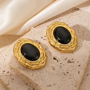 Close-up of 18K gold-plated earrings with black gemstone and vintage relief texture