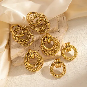 Detail von goldenen Hohlring-Ohrringen mit Perlenstruktur und verschlungenem Kreisdesign