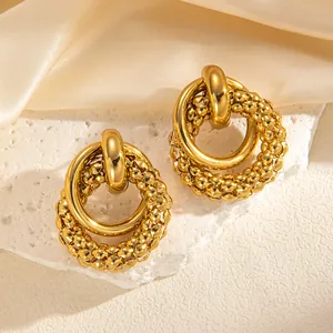 Detailaufnahme der goldenen Vintage-Ohrringe mit verschachtelten Ringen und Perlenstruktur