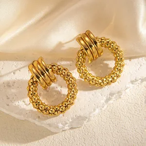 Detailaufnahme goldener Vintage-Hohlohrringe auf Marmorständer und Seide