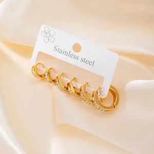 Macro view of gold stainless steel hoop earrings set with sparkling zircon stones