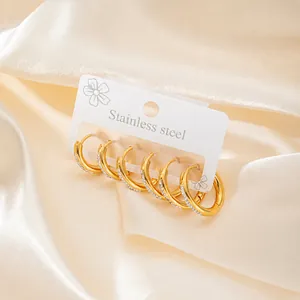 Detailed view of three pairs of gold-plated stainless steel hoop earrings with zircons