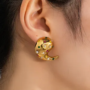 Détail de boucles d'oreilles dorées à spirale avec strass colorés et gravures étoiles