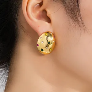 Gros plan détaillé des boucles d'oreilles dorées en acier avec des pierres de zircon colorées