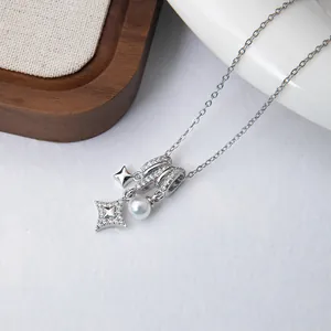 Macro detail of silver-tone necklace with zircon star pendant and round white pearl