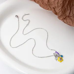Detail of silver chain necklace with yellow flower, pink heart, and blue teardrop charms