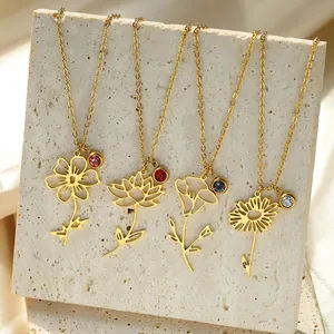 Detail of four gold floral necklaces with colorful gemstones on a beige stone surface