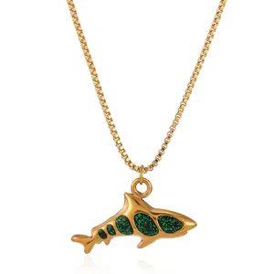 Macro view of gold shark pendant with sparkling dark green glitter and box chain detail