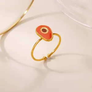 Detail of gold-plated open ring featuring a vibrant orange enamel droplet and center bead
