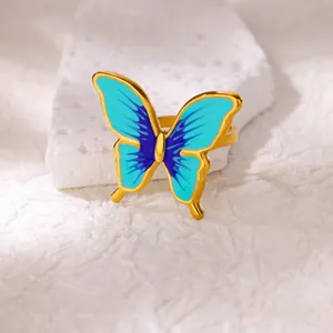 Detailed close-up of blue enamel butterfly ring with gold plating on a textured stone