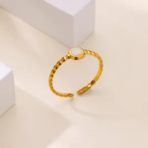 Detail of gold open ring with a square white shell inlay on a textured beaded band