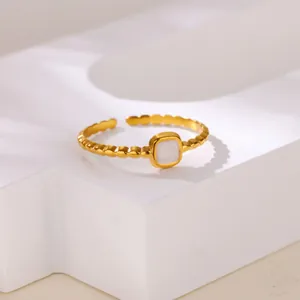 Detailed macro shot of a gold beaded ring with a square white enamel inlay on a pedestal