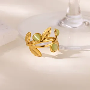Elegant gold leaf ring with light green cat eye stones on a white stone pedestal