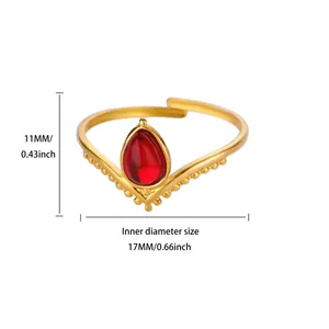 Macro shot of V-shaped gold ring featuring a teardrop red gemstone and beaded edges