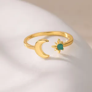Detail of moon and star ring with green gemstone on marble background