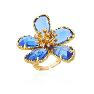 Elegant gold flower ring featuring blue crystal petals and an adjustable open band