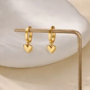 Gepolijste 18K vergulde hart oorbellen op een minimalistische displaystand