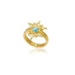 Detail of a gold flower ring with a light blue round gemstone and triple-layered band