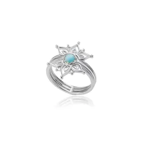 Macro detail of silver floral ring with intricate hollow petals and blue moonstone center