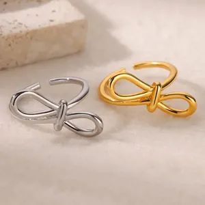 Vue macro de bagues ouvertes minimalistes en forme de nœud en or et argent sur pierre