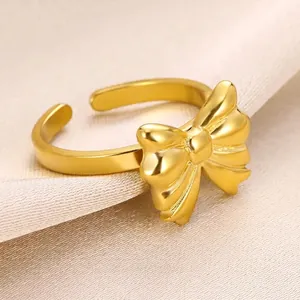 Détail d'une bague nœud dorée mate sur soie beige montrant la texture raffinée