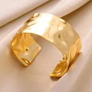 Macro shot of gold wide open cuff bracelet with irregular hammered texture on silk