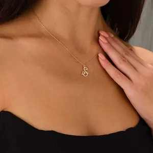 Detail of gold stainless steel 'S' letter pendant with butterfly accent on model