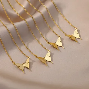 Elegante collar de mariposa dorada con iniciales grabadas sobre tela de satén