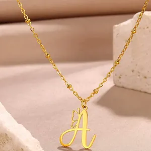 Macro detail of gold-plated letter A pendant with镂空butterfly on a beaded chain necklace