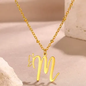Detailed macro shot of a gold letter M pendant with a butterfly on a beaded satellite chain