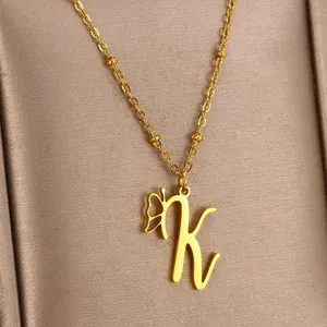 Macro shot of gold letter K and butterfly pendant on beaded chain necklace