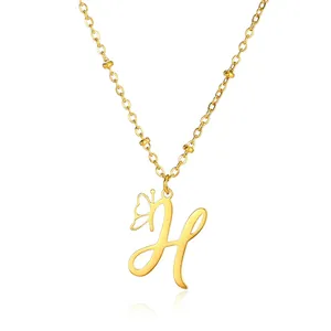 Macro view of gold stainless steel necklace with cursive letter H and butterfly charm detail