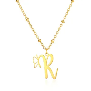 Detail of polished gold letter R pendant with cutout butterfly on a beaded chain necklace