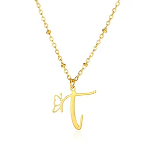 Close-up of golden necklace with butterfly charm and letter T pendant on chain