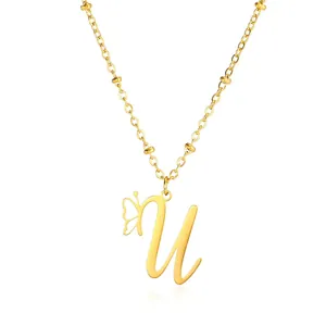 Macro detail of gold stainless steel necklace with letter U pendant and butterfly charm