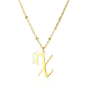 Macro shot of gold letter X pendant with butterfly wing detail and beaded chain