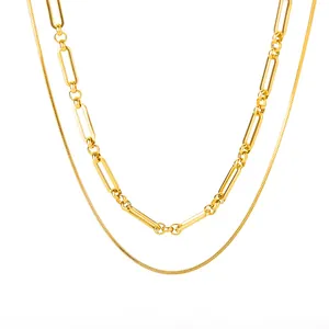 Détail de bijoux superposés plaqués or 18K avec textures de chaînes serpent et trombone